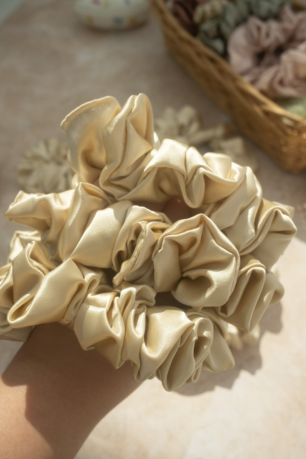 Gold scrunchies on a light surface with a blurred background