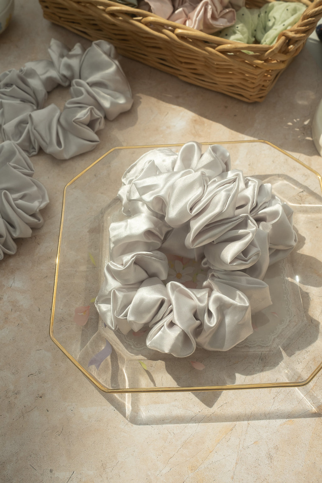 White scrunchies on a glass surface with a wicker basket in the background