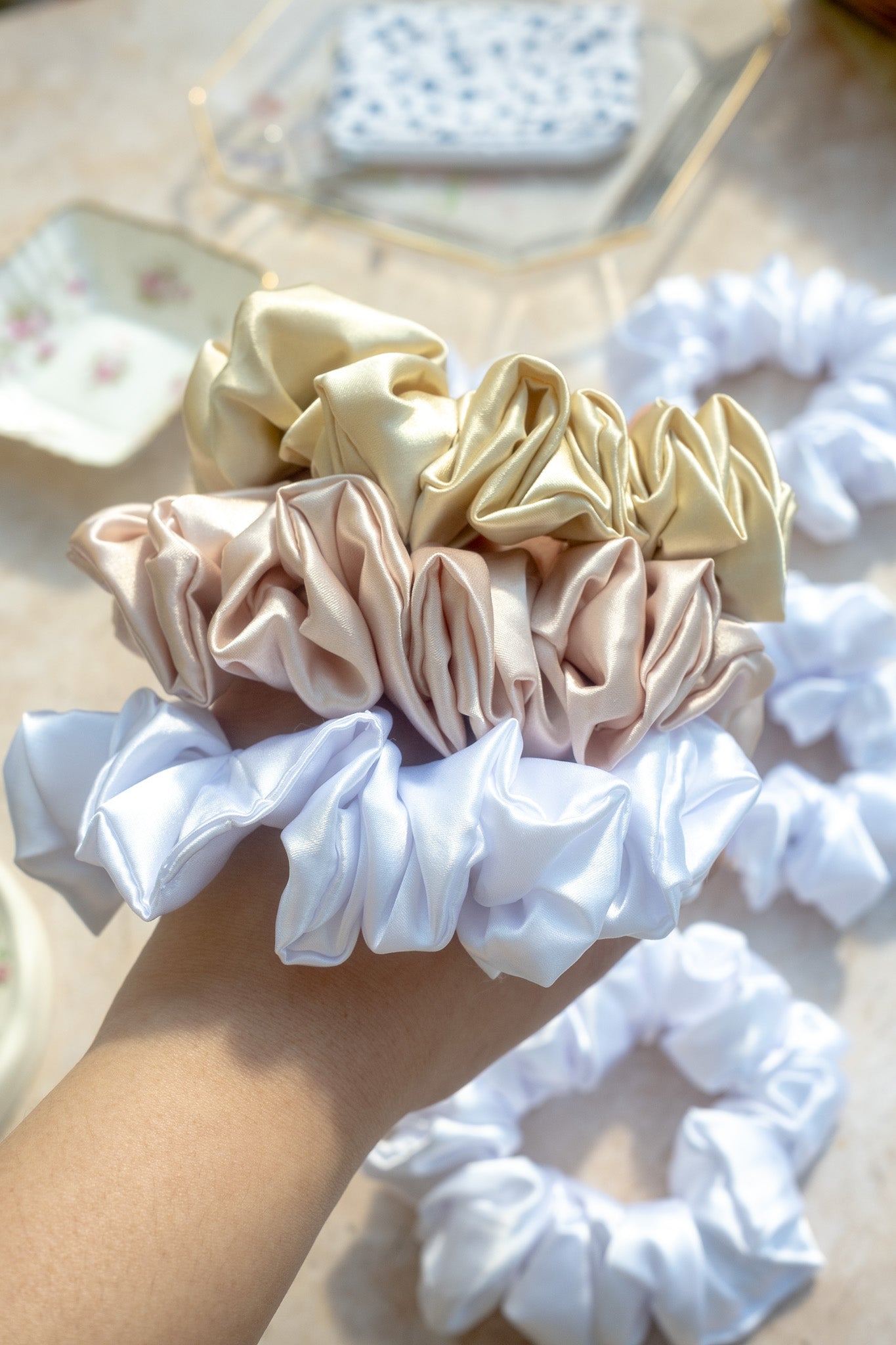 Collection of white, beige, and pink scrunchies on a light surface.