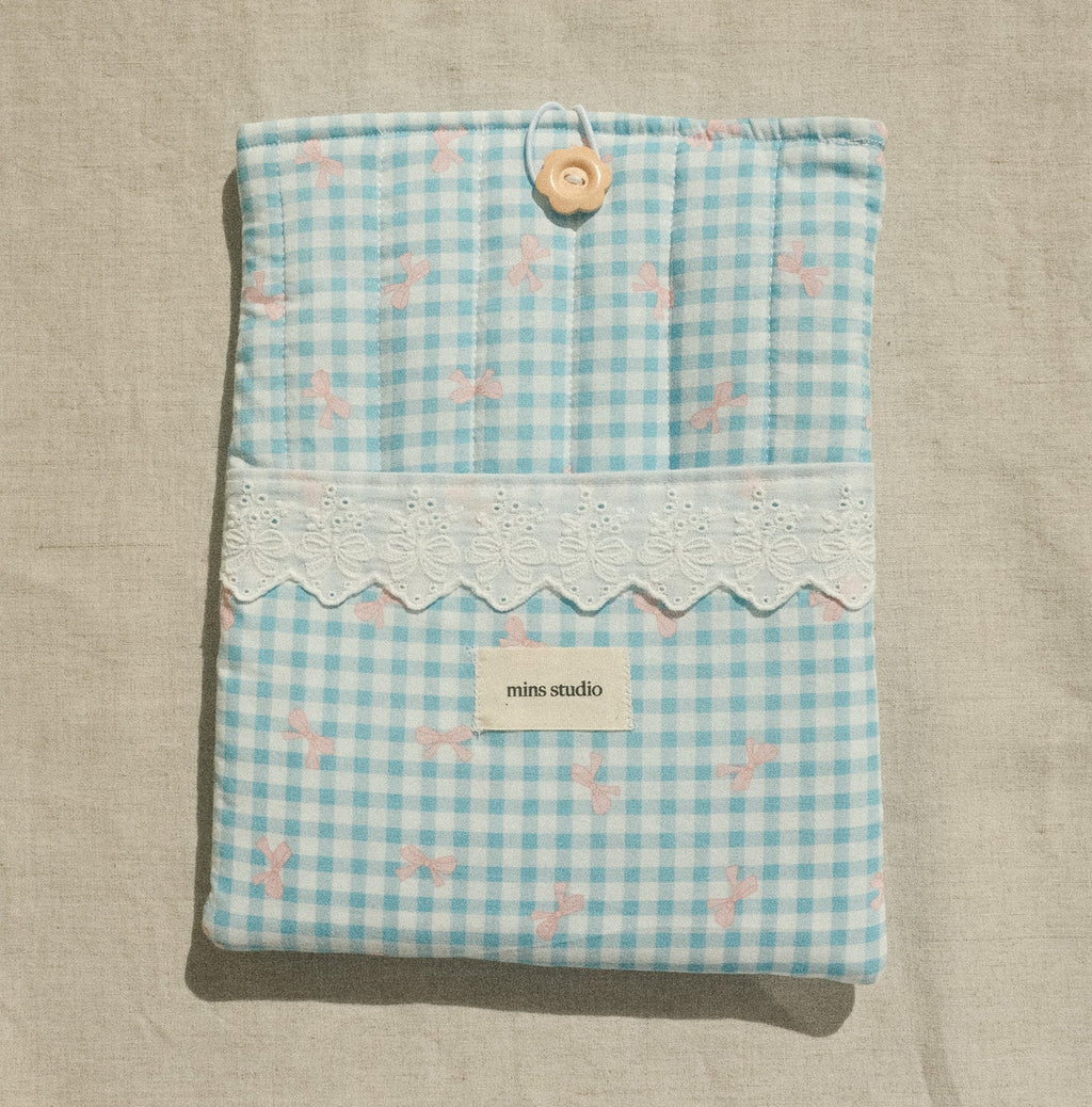 Light blue checkered pouch with a button on a beige background