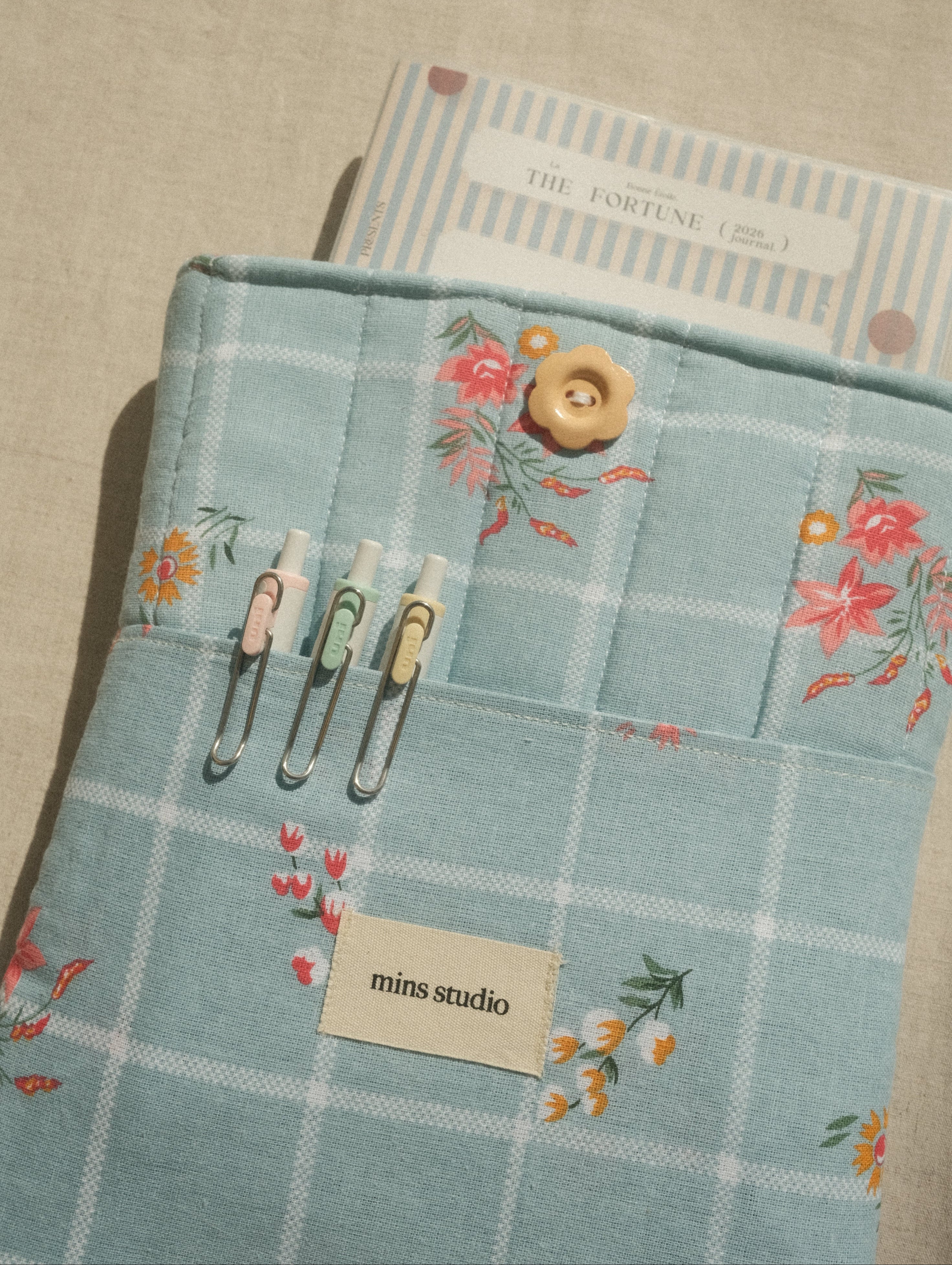 Floral-patterned fabric with buttons and a buttonhole on a textured surface