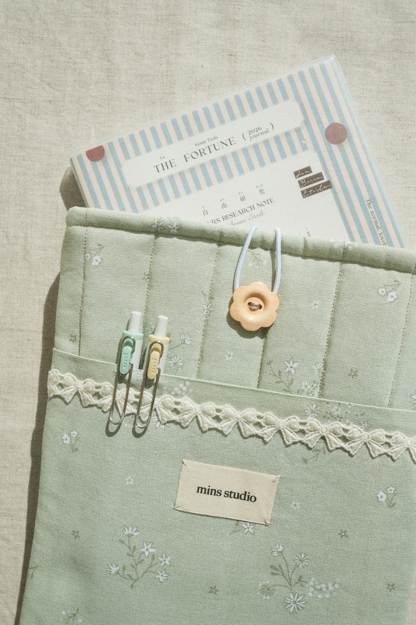 Sage booksleeve with diary inside and two pens in the front pocket
