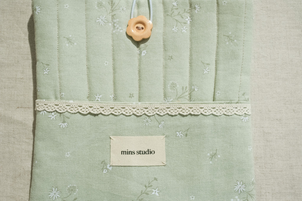 Sage book sleeve with a lace and brand label