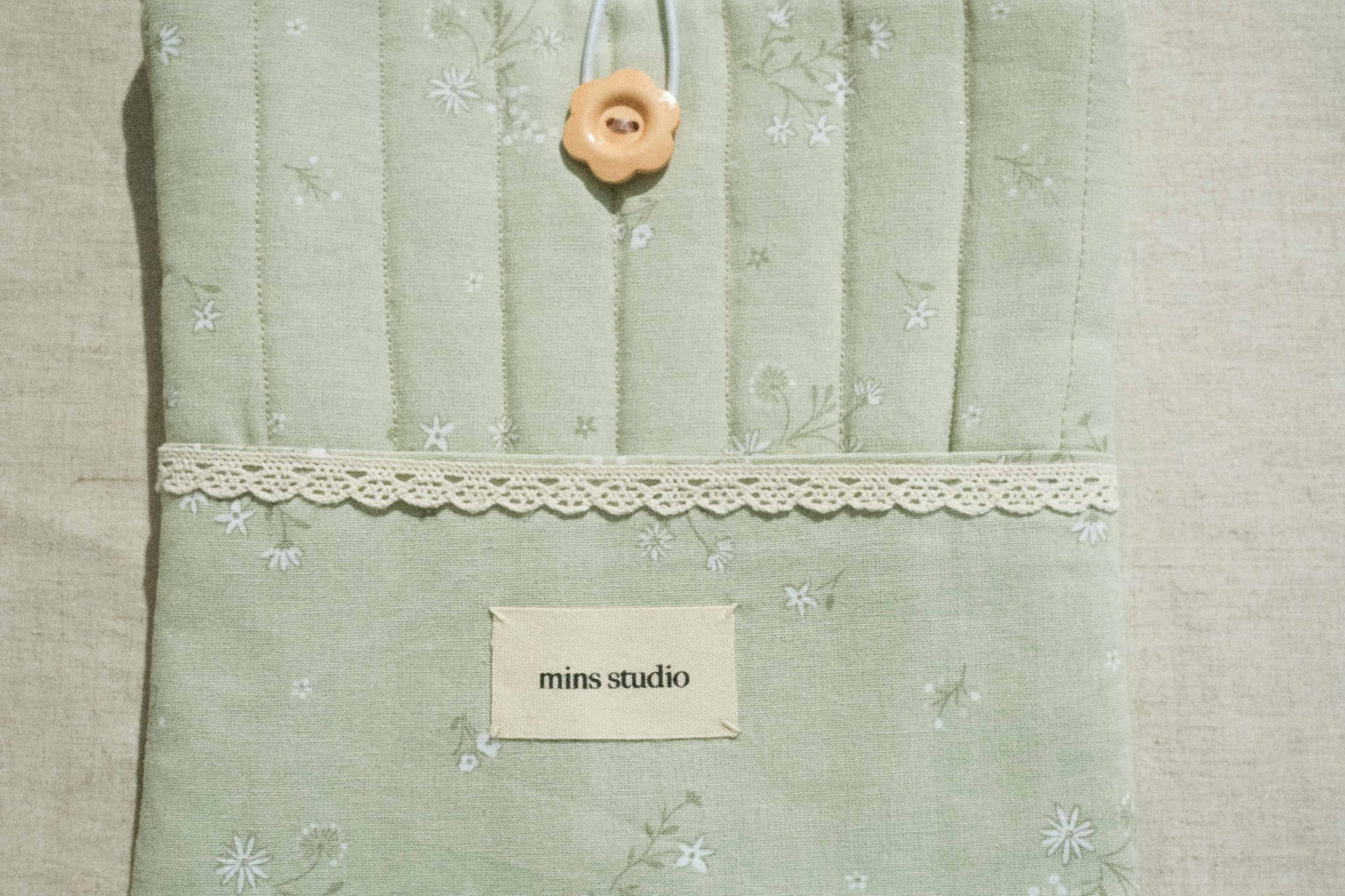 Sage book sleeve with a lace and brand label