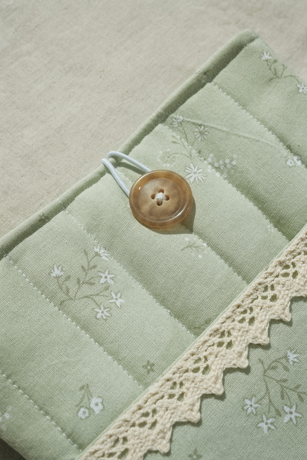 Sage booksleeve close up on button and lace detail