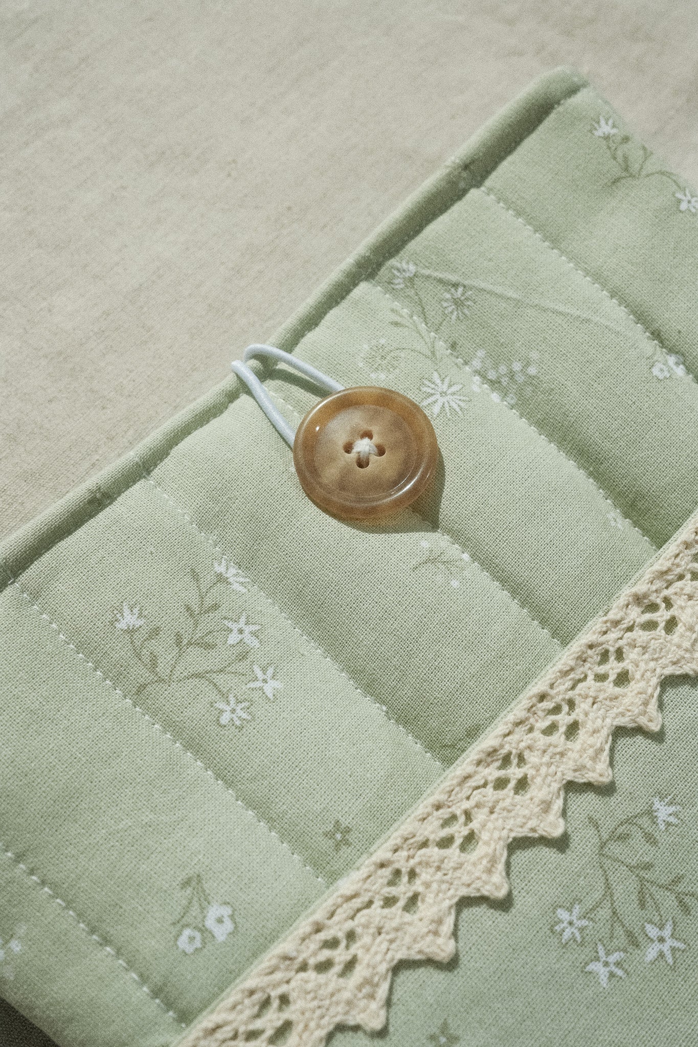 Sage booksleeve close up on button and lace detail