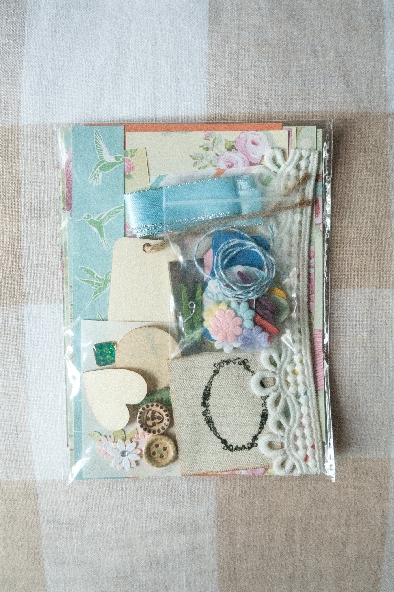 Collection of decorative items including a necklace, flowers, and ribbons on a checkered fabric background.