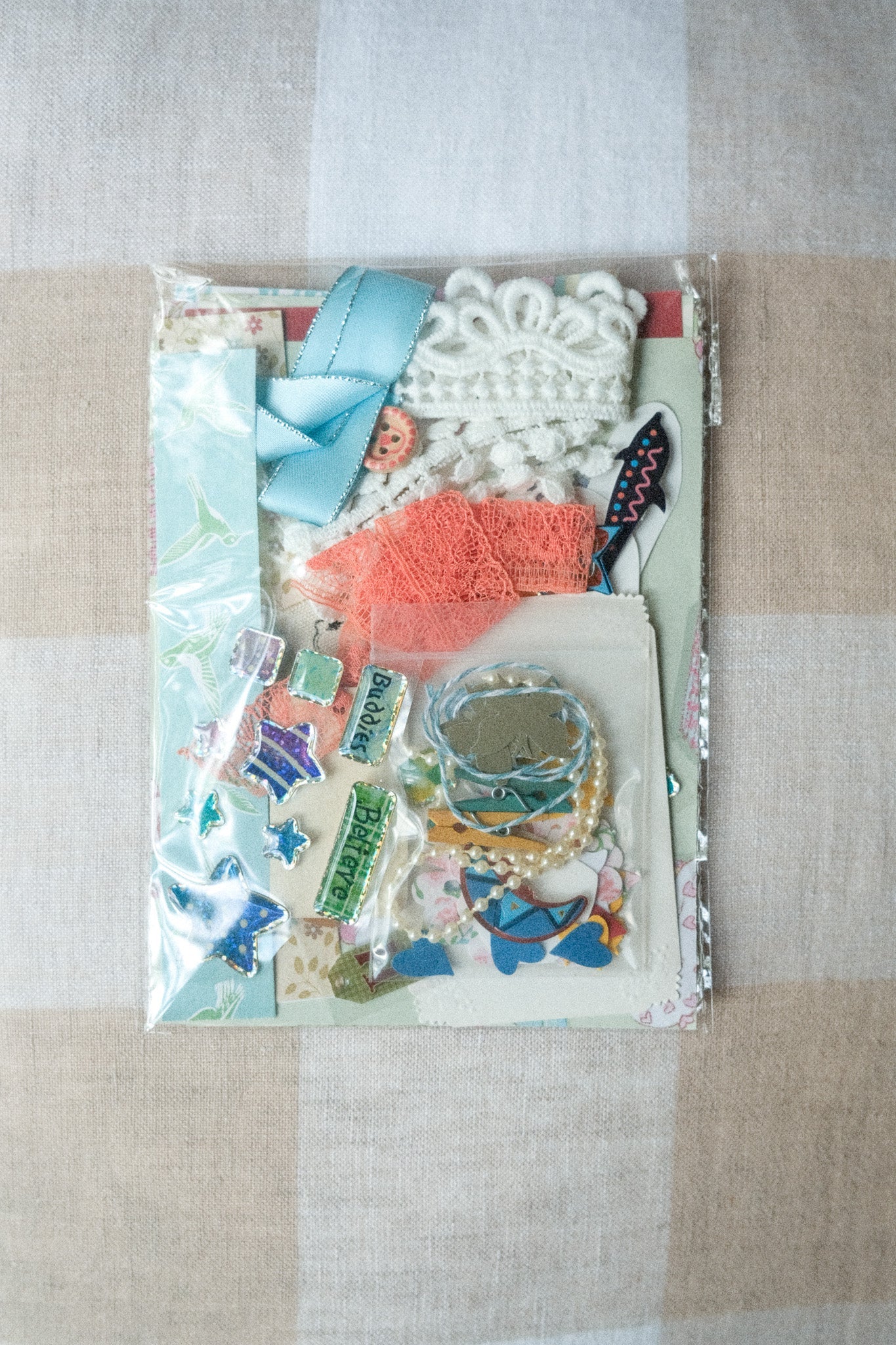 Packaged craft supplies including ribbons and decorative items on a checkered fabric background