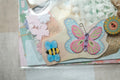 Decorative card with butterfly and bee embellishments on a textured surface