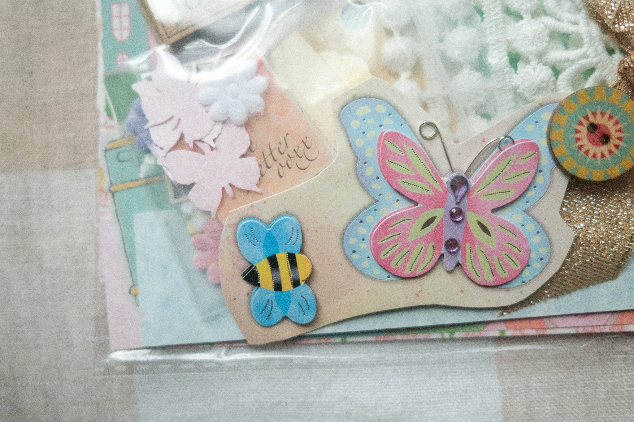 Decorative card with butterfly and bee embellishments on a textured surface