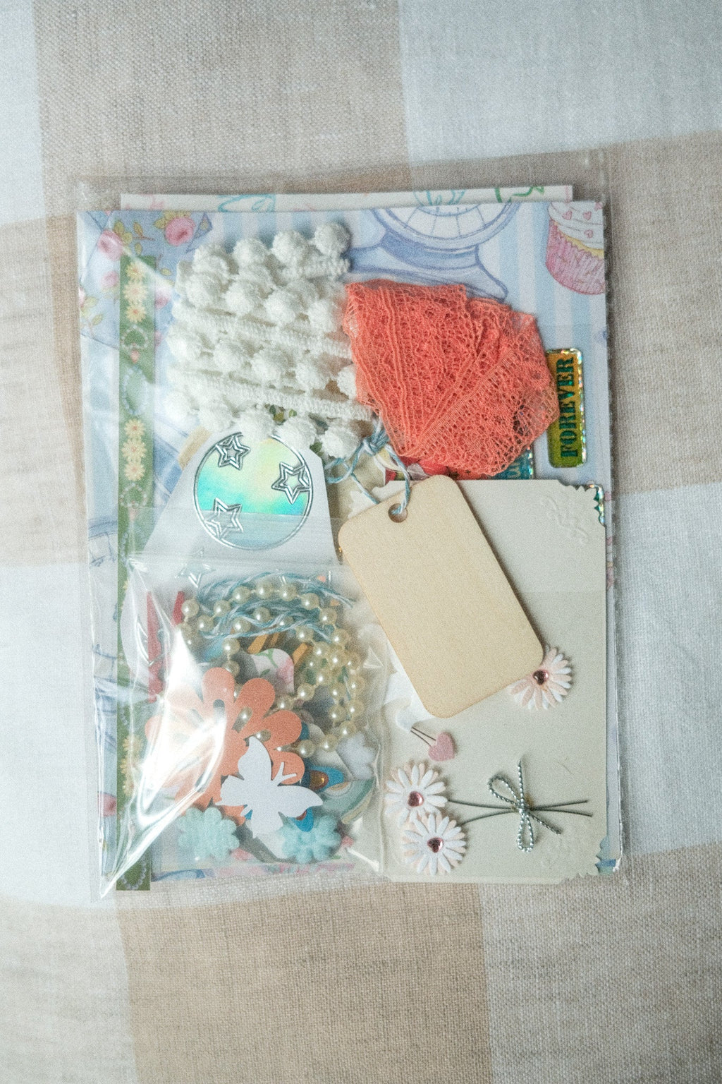 Decorative paper craft kit with flowers, tags, and ribbons on a textured surface