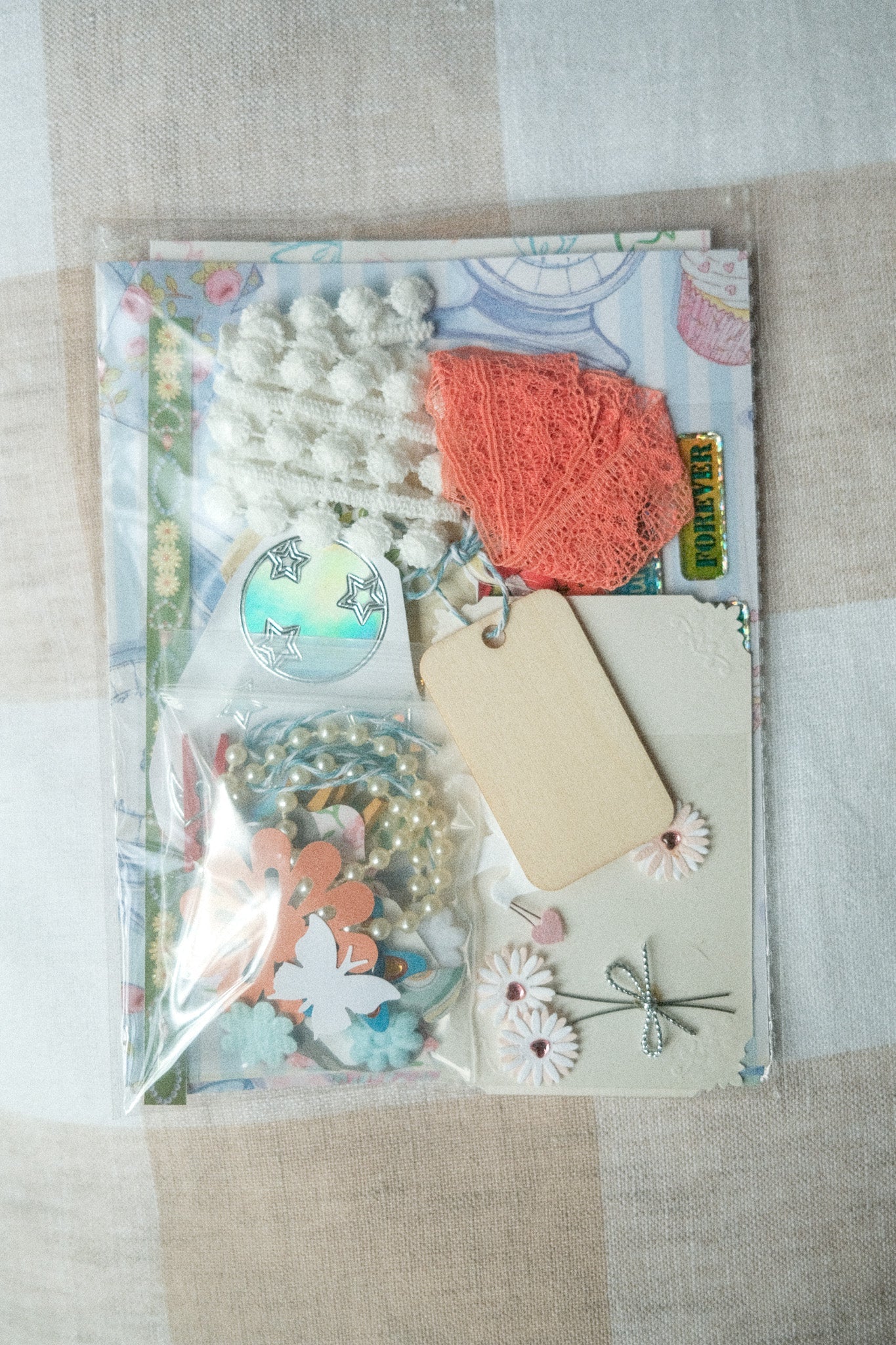 Decorative paper craft kit with flowers, tags, and ribbons on a textured surface