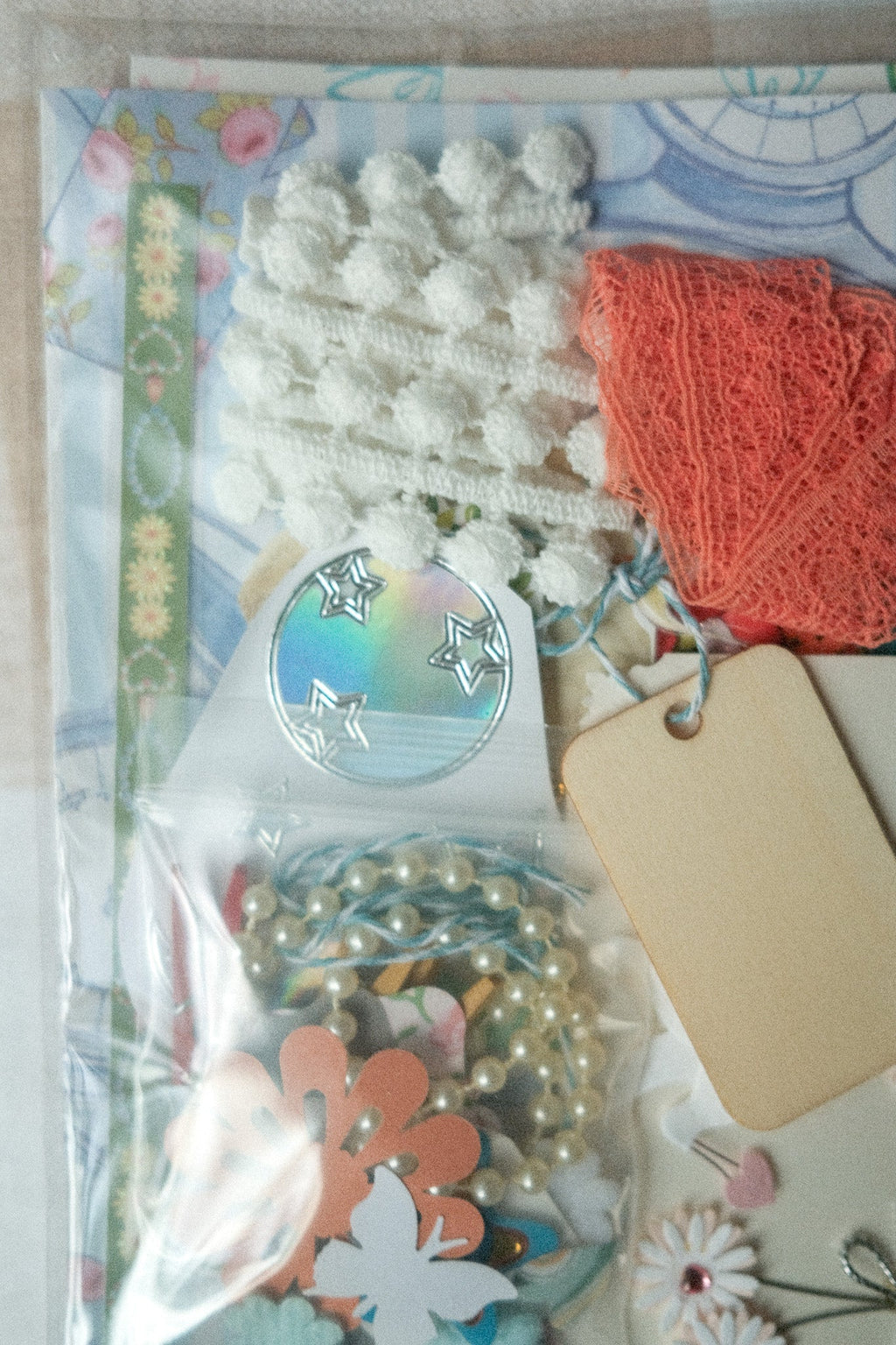 Assorted craft supplies including flowers, ribbons, and decorative elements on a floral background.