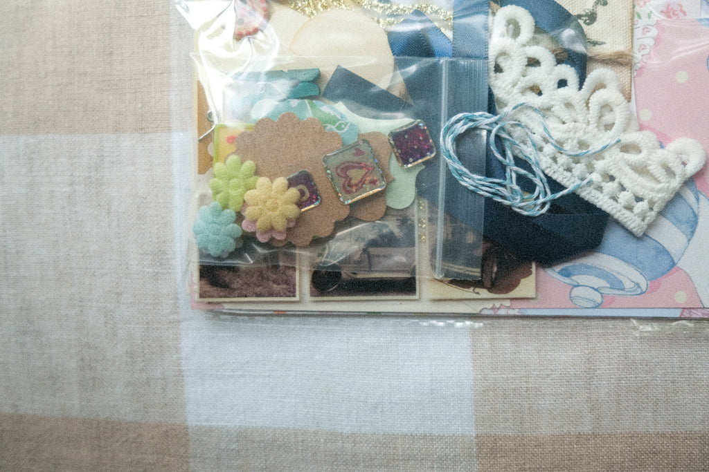 Scrapbooking supplies including stickers and lace on a textured surface