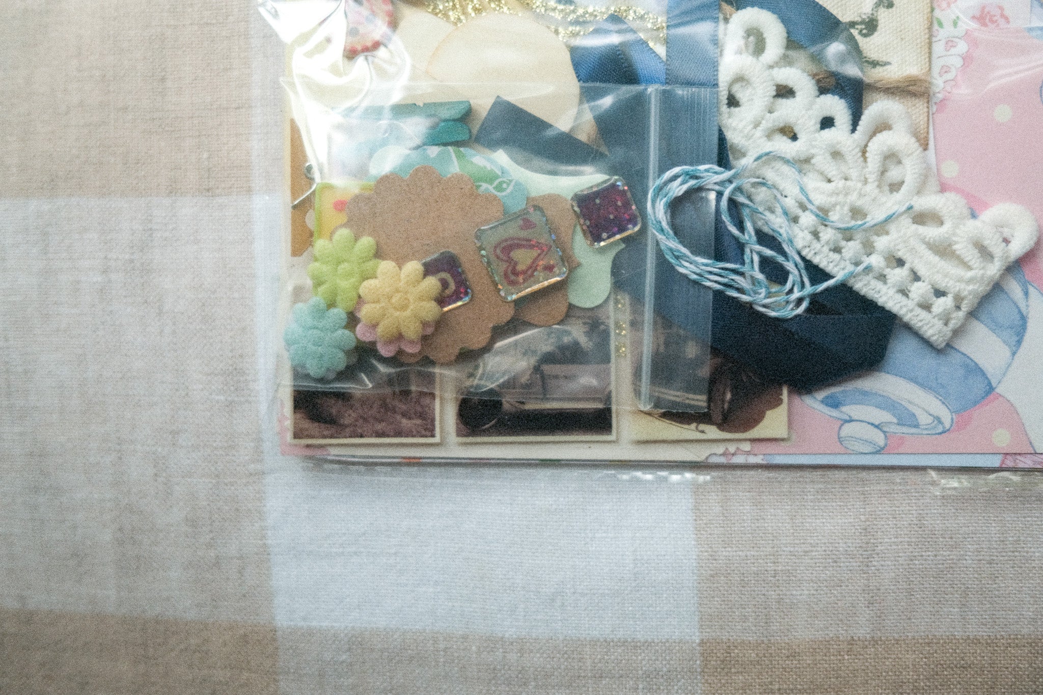 Scrapbooking supplies including stickers and lace on a textured surface