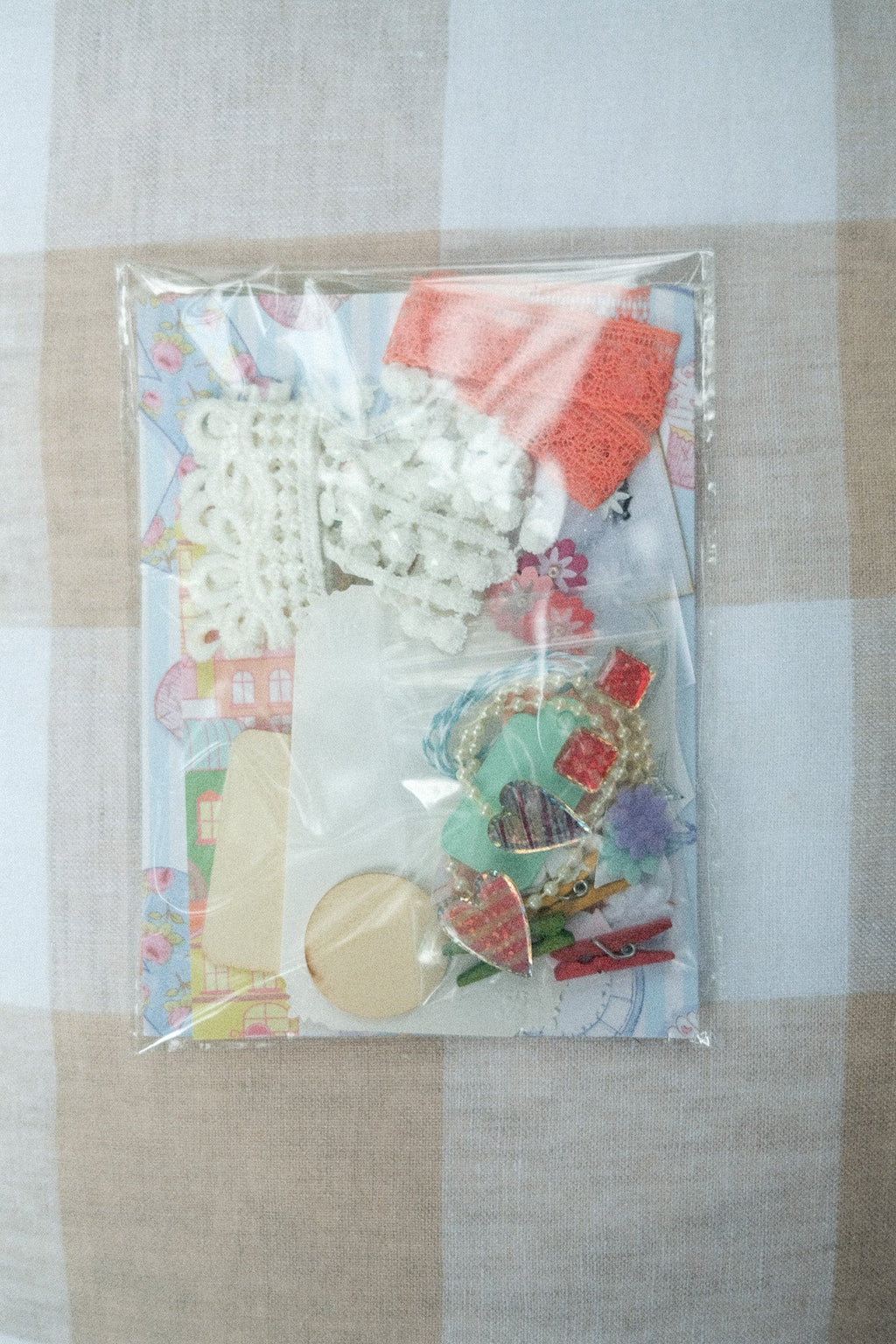 Packaged craft supplies including buttons and beads on a checkered fabric background