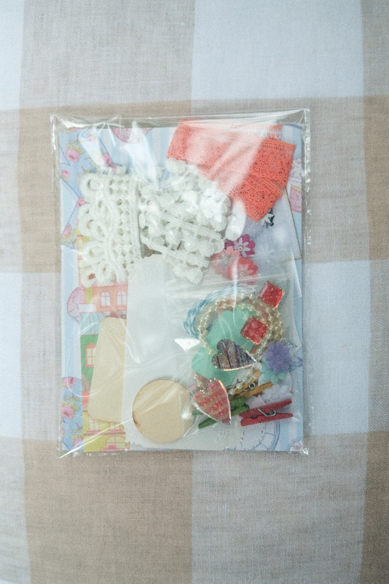 Packaged craft supplies including buttons and beads on a checkered fabric background