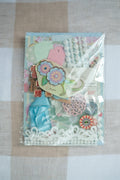 Packaged craft supplies with decorative elements on a checkered fabric background