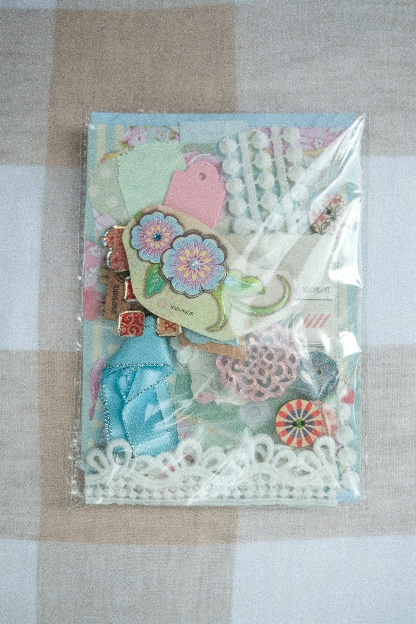 Packaged craft supplies with decorative elements on a checkered fabric background