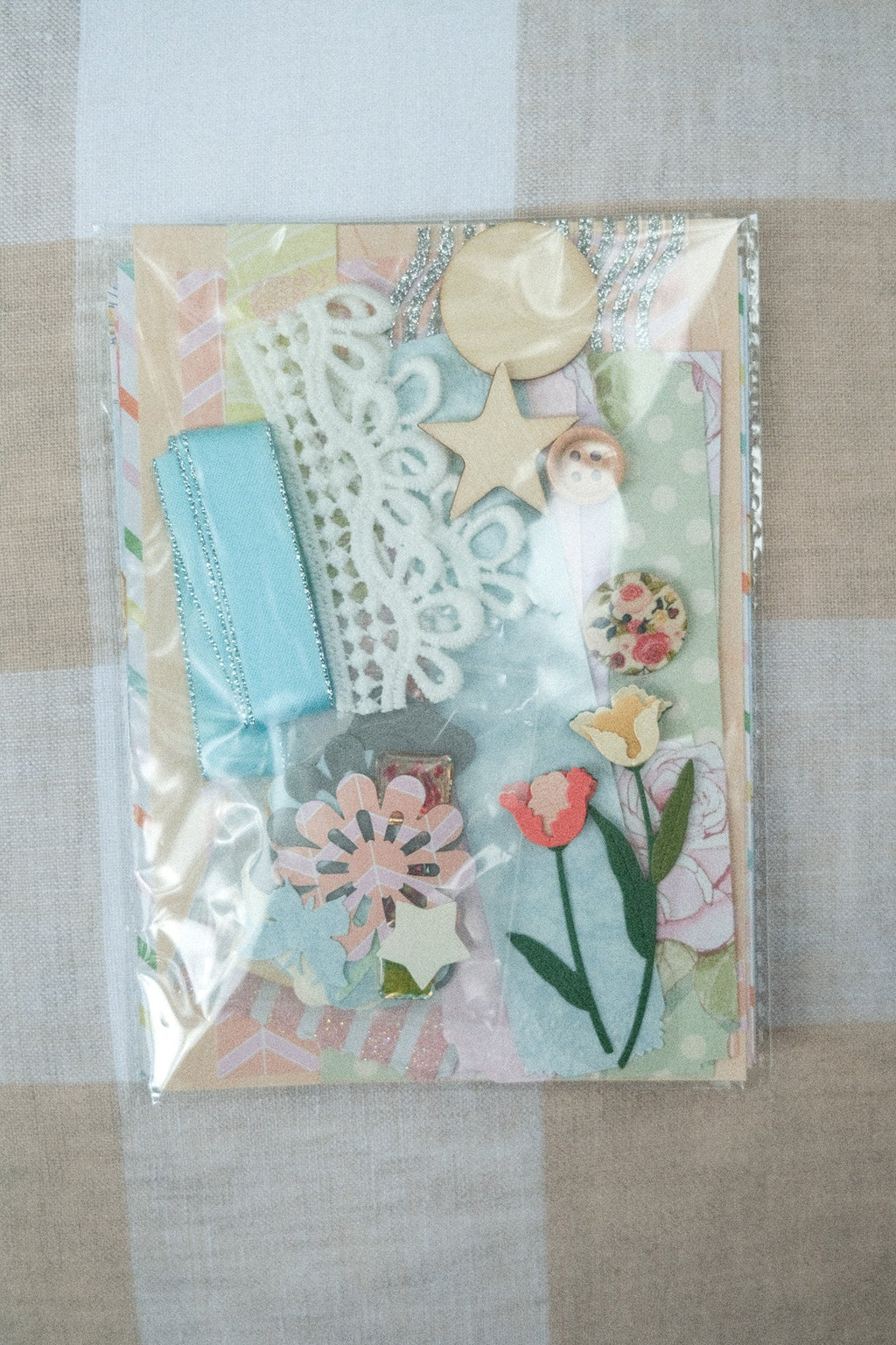 Decorative card with floral and beach-themed elements on a checkered fabric background