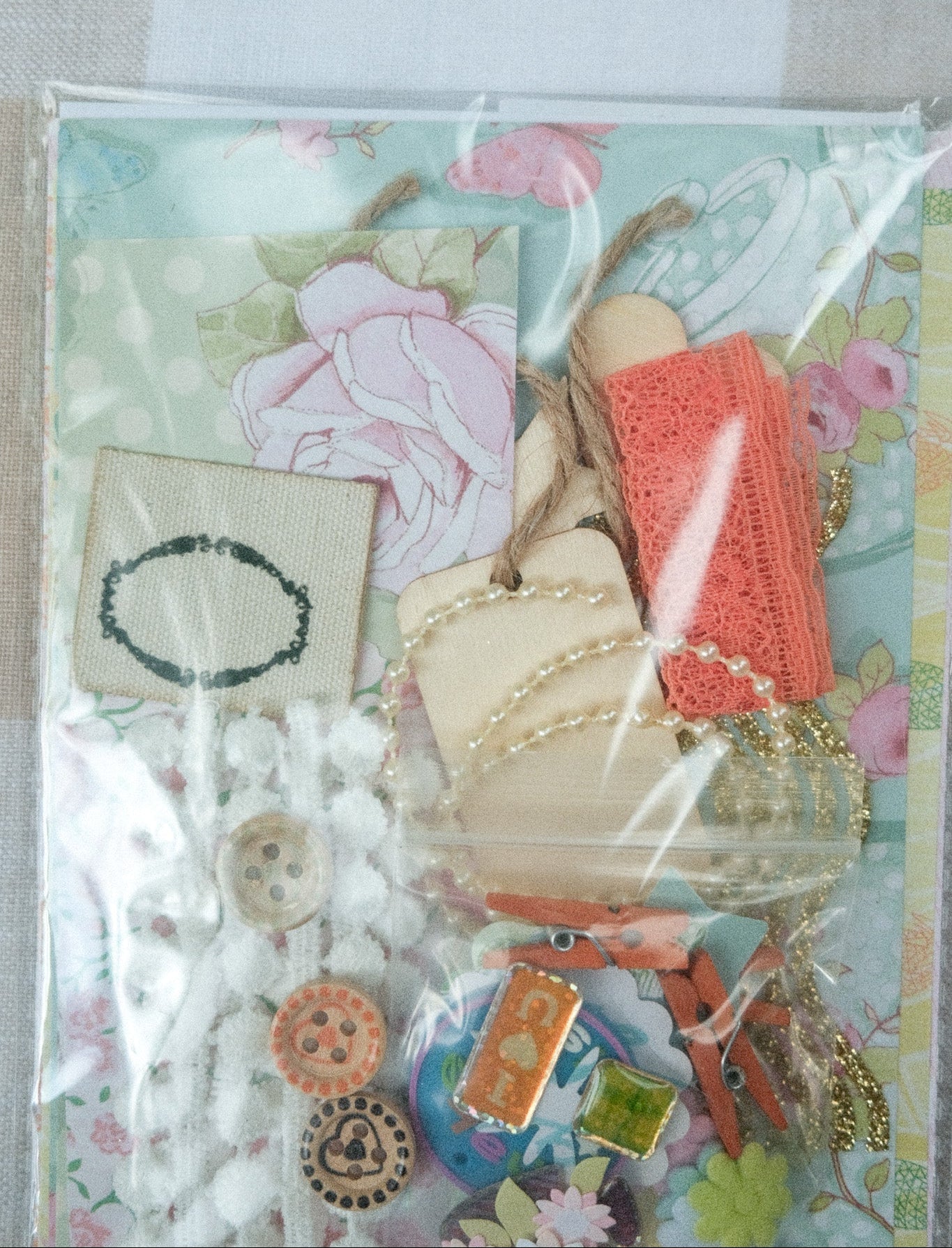 Collection of decorative items including buttons, ribbons, and a card with flowers on a floral-patterned background.
