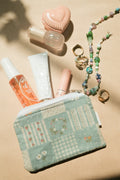 Small pouch with cosmetic items and jewelry on a beige surface