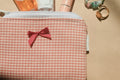 Checkered pouch with a red bow on a beige background
