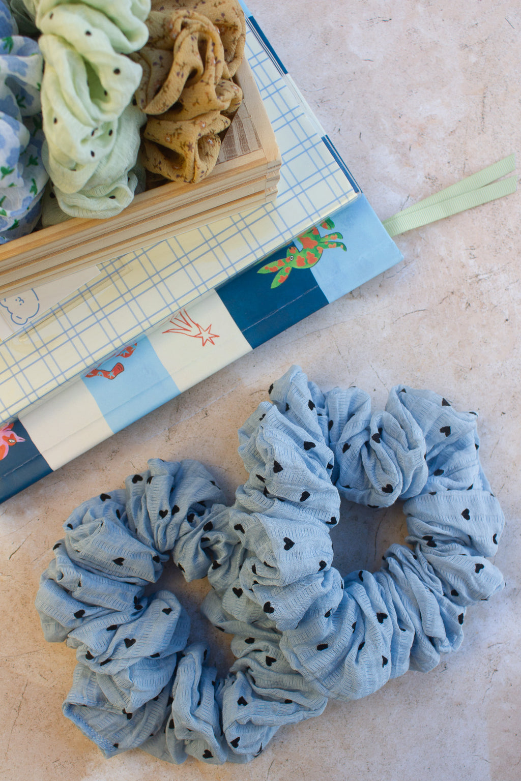 Blue scrunchie with black polka dots on a textured surface