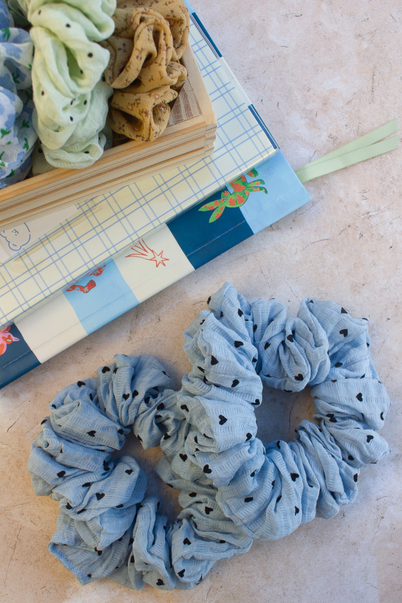 Blue scrunchie with black polka dots on a textured surface