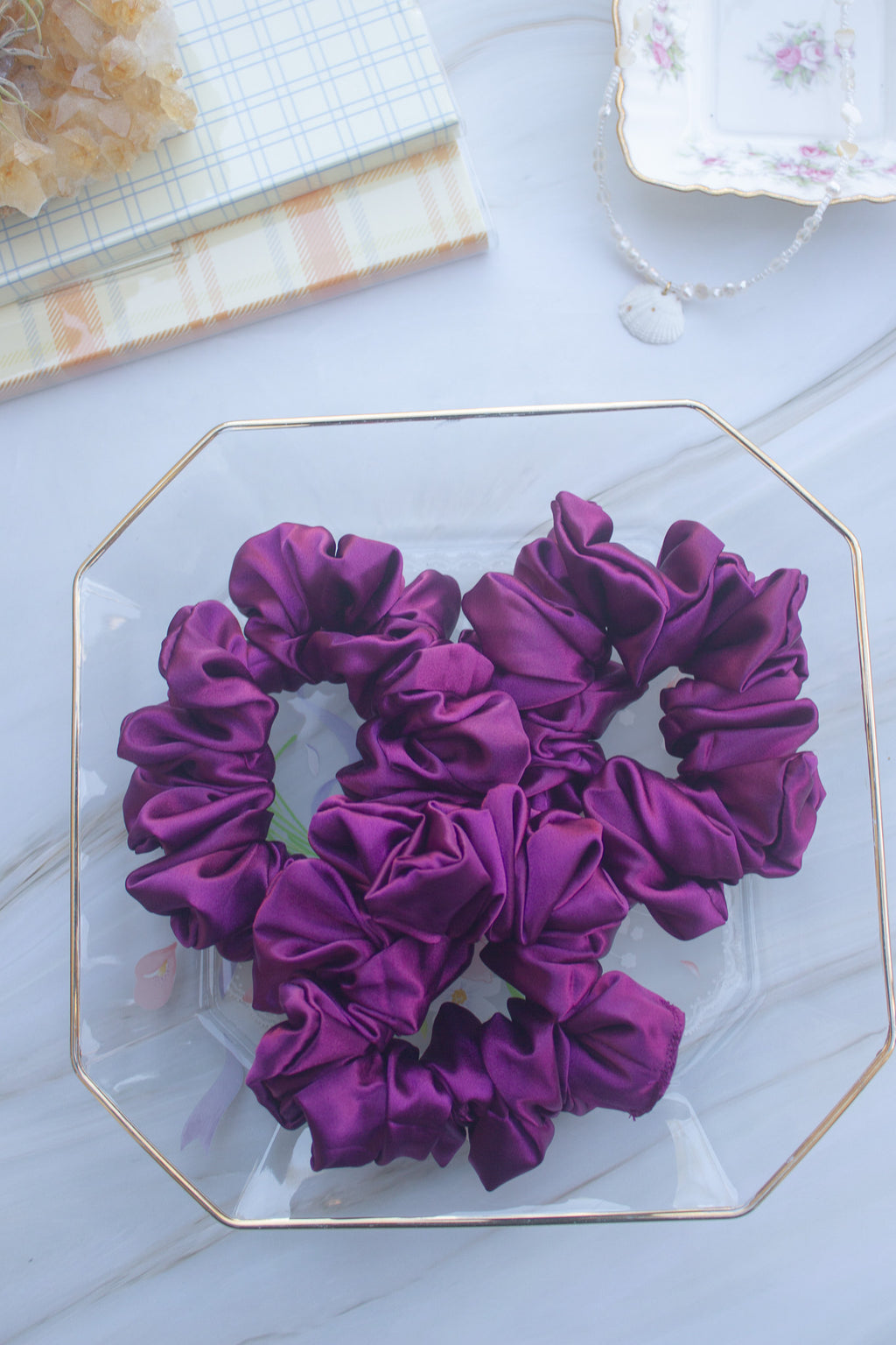 Purple scrunchies on a decorative glass plate with a light background